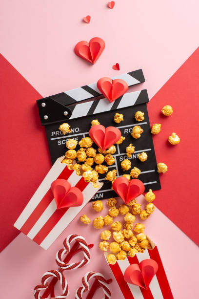 istock A vertical creative movie night setting with popcorn, a clapperboard, and red paper hearts, perfect for Valentine's Day. Enhances romantic vibes with a red and pink background 2190654178