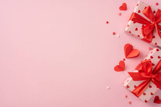 istock Romantic Valentine's Day scene featuring beautifully wrapped gift boxes with red ribbons and heart decorations on a soft pink background, perfect for expressing love and affection 2190654254