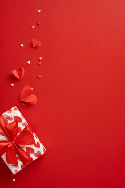 istock A vertical romantic Valentine's Day scene with a beautifully wrapped gift box, red hearts, and paper decorations on a red background, perfect for expressing love and affection 2190654255