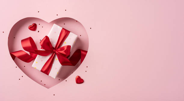 istock A beautifully wrapped gift box with a red ribbon, surrounded by a heart-shaped cutout on a pink background, perfect for Valentine's Day celebrations 2190654283