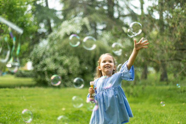 istock Little girl playing with soap bubbles in park during summer day 2190654645