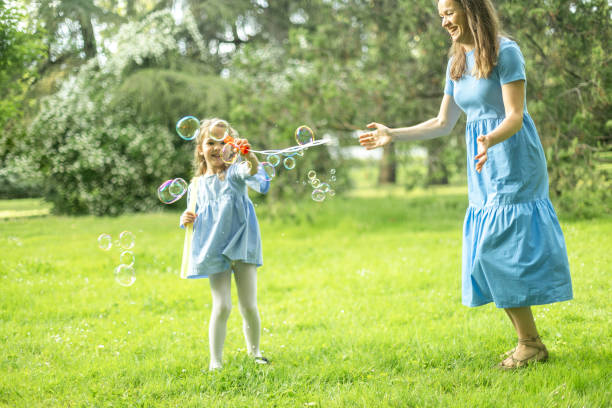 istock Little girl making soap bubbles with her mother in a park 2190654662