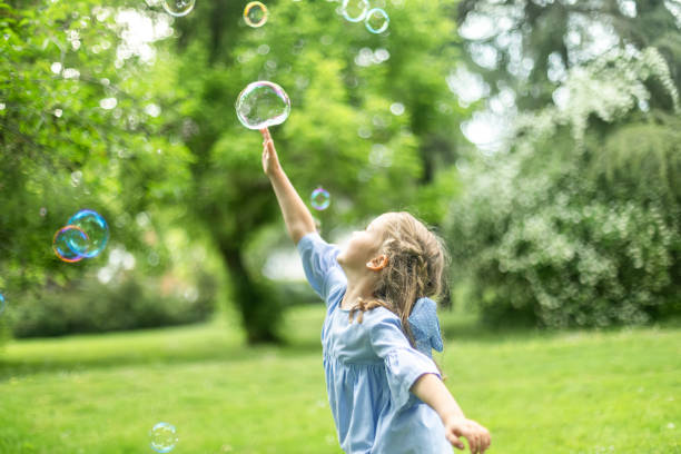 istock Little girl playing with soap bubbles in green park 2190654670