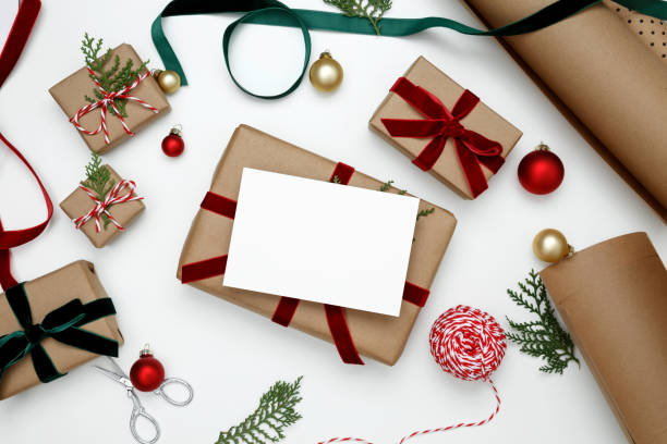 istock Christmas gift mockup with white card on top, surrounded by holiday wrapping materials and decorations 2190655531