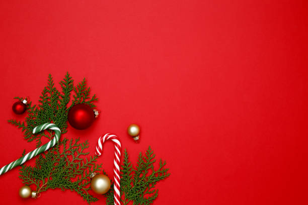 istock Christmas ornaments, thuja branches, and candy cane arranged on a red background for festive holiday decor 2190655592