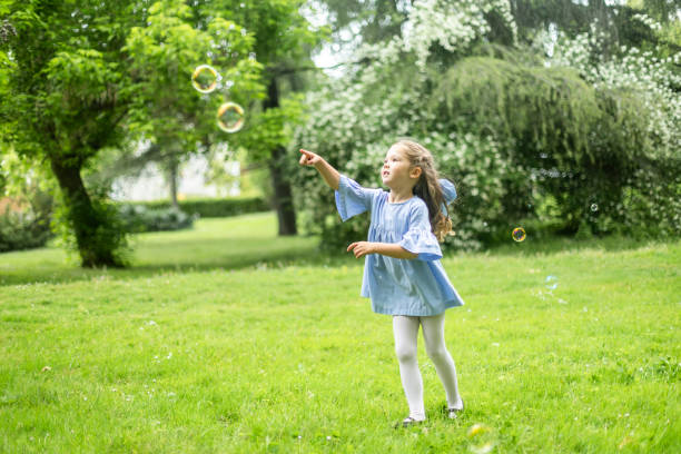 istock Little girl playing with soap bubbles in green park during summertime 2190656152