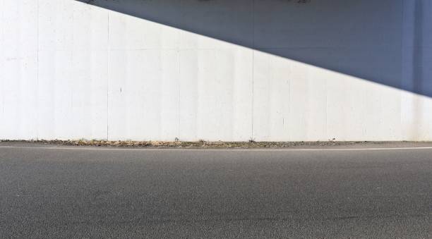 istock White prefab concrete wall divided by  shadow and sunlight at the roadside. 2190658062