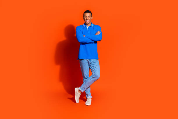 istock Smiling young man in vibrant blue shirt posing against a bright orange backdrop 2190658824