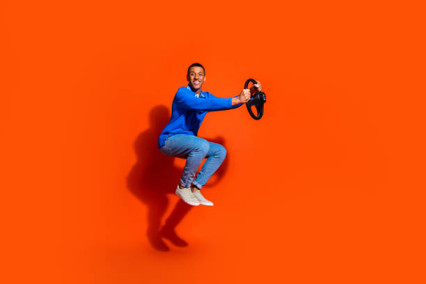 istock Happy young man in blue shirt posing joyfully against vibrant orange backdrop 2190658876