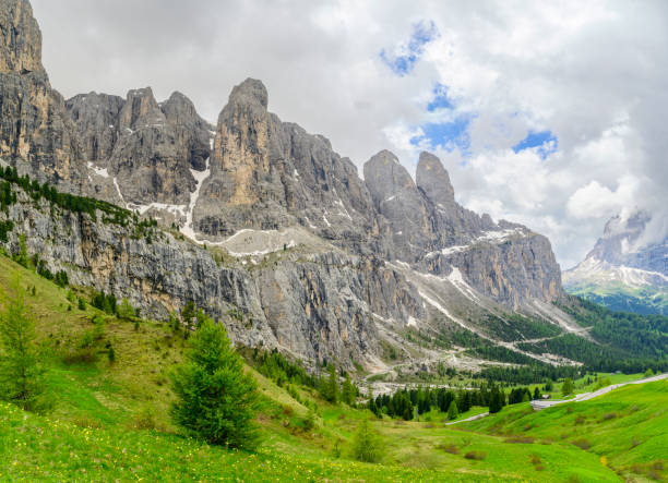Sella group plateau-shaped massif in the Dolomites mountains  seen from the Val Gardena during a sprintime day in the Italian Alps. A footpath is winding through the Alpine meadow alms.