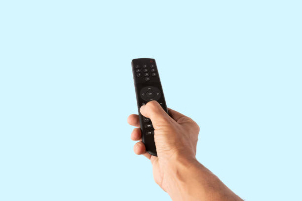 istock Male hand holding a tv remote controller isolated on cyan background cutout 2190659727