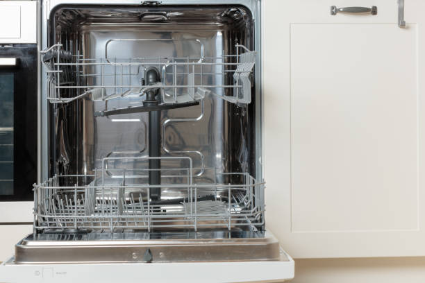 istock Built-in empty dishwasher with its door open. Modern technologies in the home kitchen with minimalistic white cabinetry. Simplifying daily housework. 2190660485