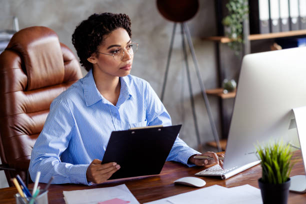 istock Confident young businesswoman reviewing documents on her desk in modern office setting 2190665636