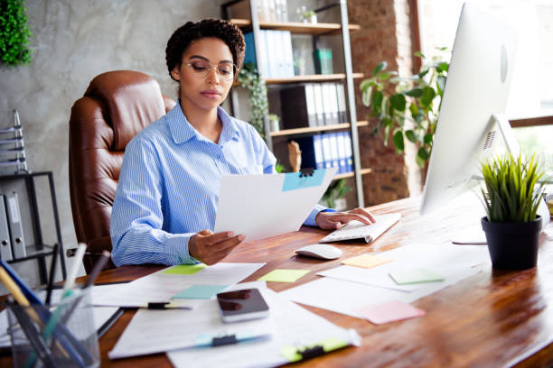 istock Focused businesswoman reviewing documents at desk in modern office workspace with elegant style and natural daylight 2190665696