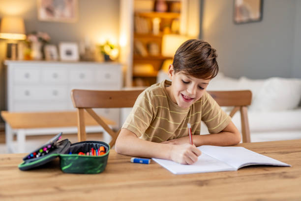 istock Elementary age boy concentrating on homework, writing in a notebook at home, immersed in learning and developing skills at his desk 2190666462