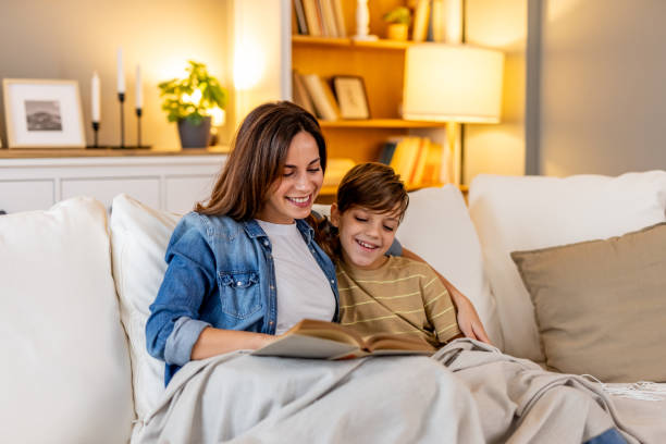 istock Mother and son enjoying quality time together, reading a book and bonding on a comfortable sofa in their cozy living room 2190666547