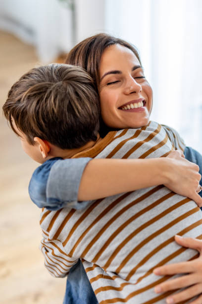 istock Mother hugging young son warmly, snuggling closely on comfortable sofa, expressing deep familial affection and emotional bond 2190666675
