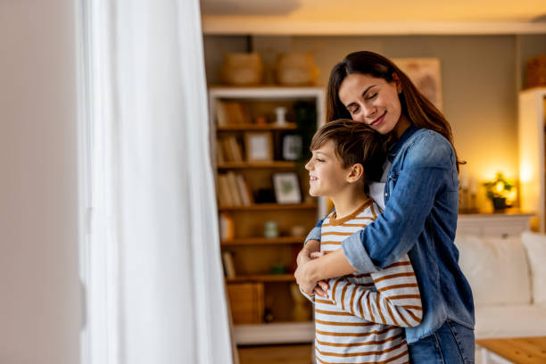 istock Mother hugging son near window, sharing tender connection and peaceful home atmosphere 2190666677