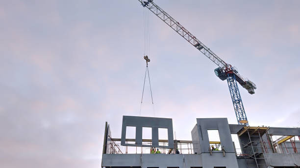 istock Construction workers lifting a concrete panel at a building site in an urban area against the sky 2190668070