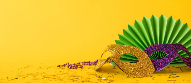istock Colorful side view glitter masks and beads arranged on a yellow background symbolizing a Mardi Gras celebration 2190668187