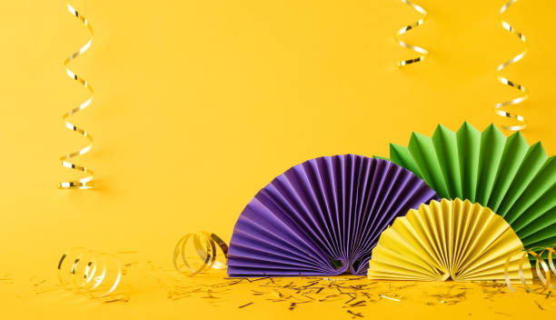 istock A bright and vibrant side view image showcasing colorful decorations on a yellow background for Mardi Gras celebration, featuring paper fans and golden streamers exuding a festive atmosphere 2190668188
