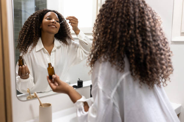 istock Young woman applying serum on her face in the bathroom mirror 2190668955