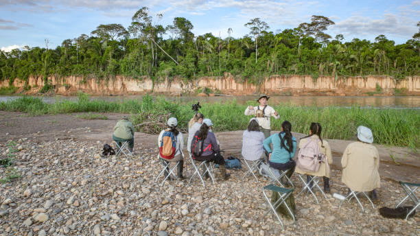 Tambopata, Peru - 27 Nov, 2024: A guide leads a group of birdwatchers  at a Macaw clay lick feeding ground in the Amazon rainforest