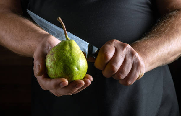 istock In a cozy kitchen, a person holds a fresh green pear in one hand while preparing to slice it with a sharp knife in the other. The atmosphere exudes a sense of culinary anticipation 2190676951