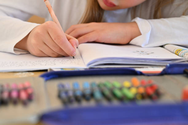 Close up shot of hand of primary school girl, doing drawings and writings during a class - no recognisable identity