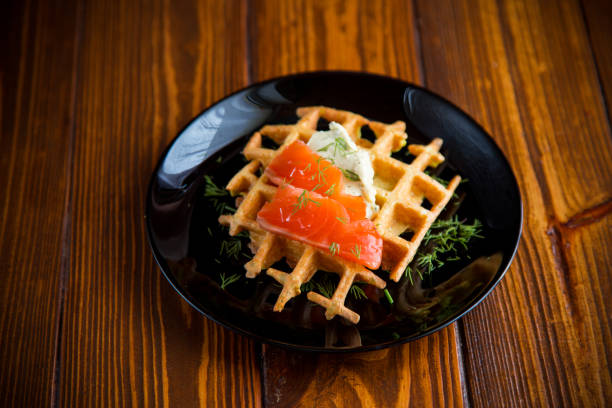 istock vegetable potato waffles with spread and lightly salted red fish, in a plate on a wooden table 2190683352