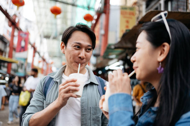 Asian couple enjoys refreshing beverages while strolling through the lively ambiance in Chinatown