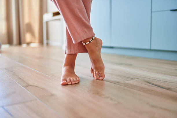 Barefoot female legs on comfortable heated warm tiles at home. Modern floor heating system in house