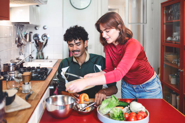 istock smiling young woman and man preparing meal in kitchen 2190686251