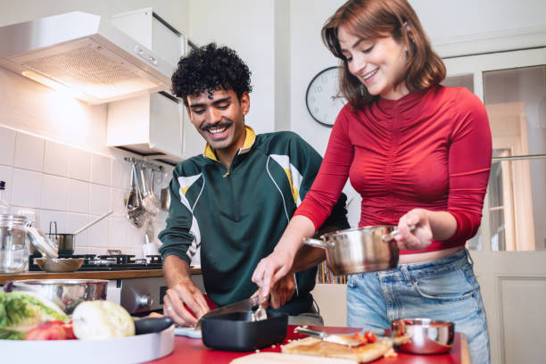 istock smiling young woman and man preparing meal in kitchen 2190686275