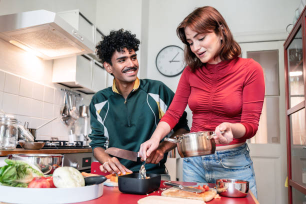 istock smiling young woman and man preparing meal in kitchen 2190686299