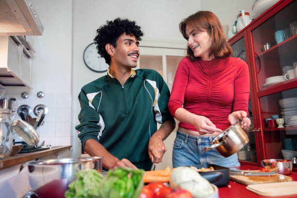 istock smiling young woman and man preparing meal in kitchen 2190686321