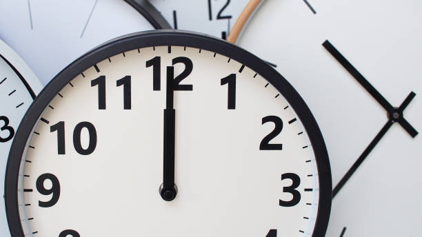 istock A collection of round wall clocks overlapping each other, with one clock prominently showing the time as 12 o'clock. Clean design with bold black numbers and hands on white dials. 2190688665