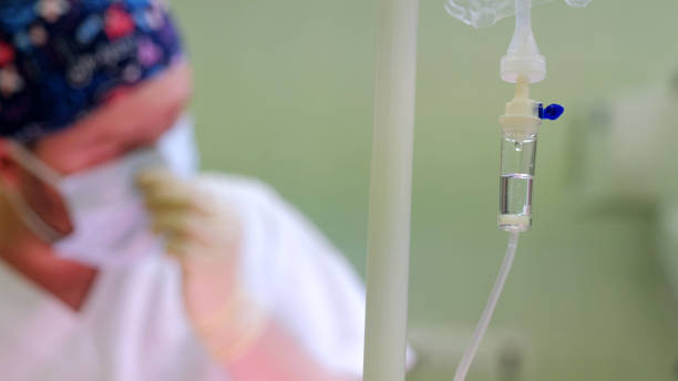 istock Anticipating a medical procedure, a blurred surgeon adjusting mask while iv drip hangs in focus 2190689225