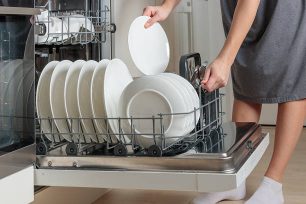 istock Female hand unloading dishwasher with tableware. Kitchen appliances, lifestyle view. Woman takes a plate from the dishwasher. Concept of modern technologies in the kitchen 2190691829