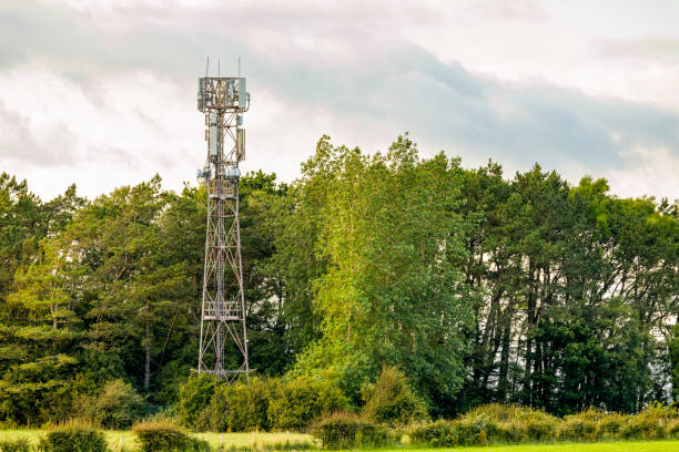 istock Mobile cell phone transmitter aerials on grey metal mast tower beside trees in field 2190692161