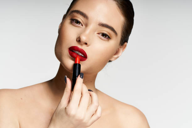 istock Captivating fashion model applying bold lipstick in studio atmosphere 2190693850