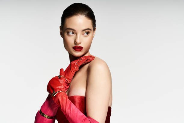 istock Chic young woman in vibrant red attire poses elegantly in a modern studio 2190693992