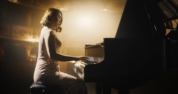 istock Portrait of a Talented Asian Pianist Captivating Audience with a Masterful Performance on a Grand Piano. Under Soft Stage Lights, Her Fingers Move Across the Keys, Creating Beautiful Classical Music 2190696849
