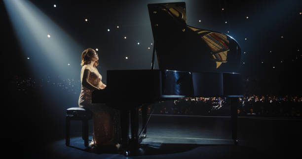 istock Portrait of a Talented Asian Pianist Captivating Audience with a Masterful Performance on a Grand Piano. Under Soft Stage Lights, Her Fingers Move Across the Keys, Creating Beautiful Classical Music 2190697689