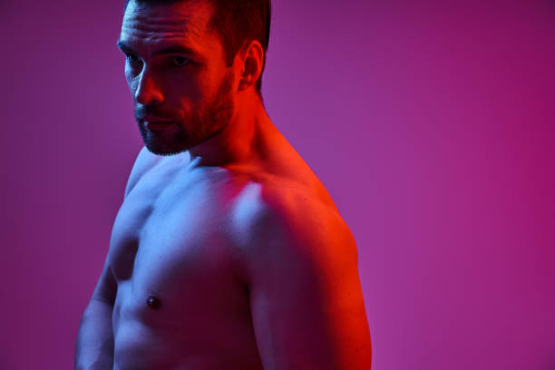 istock Stylish young man showcasing confidence in vibrant lighting with a modern twist 2190699530