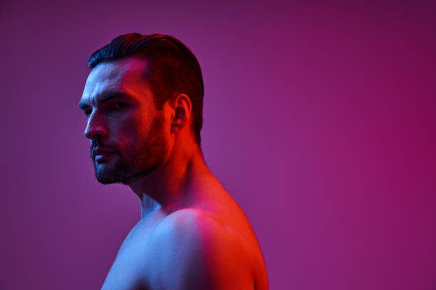 istock Stylish young man with striking features poses against a colorful, dramatic backdrop 2190699728