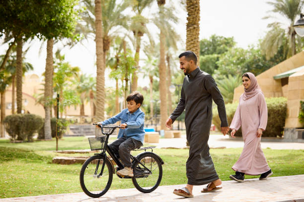 Father and son teaching their son cycling at park