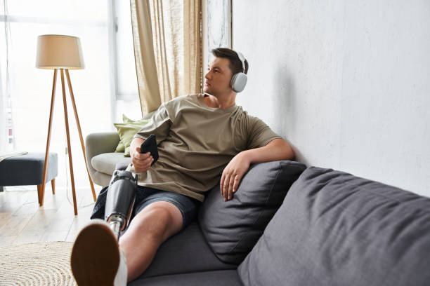 istock Young man enjoying music comfortably at home with prosthetic leg 2190703621