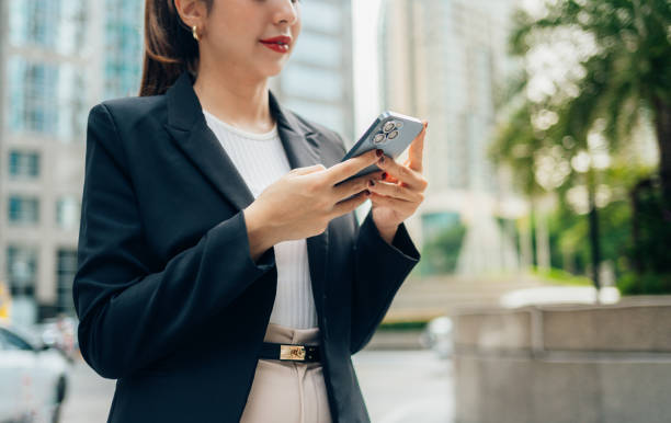 istock Businesswoman standing in an urban environment, using a smartphone while dressed in a stylish blazer and elegant trousers, engaging in communication and browsing online 2190706432
