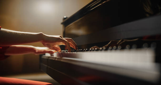 istock Close Up on Hands of a Talented Anonymous Pianist Making a Masterful Performance on a Grand Piano. Under Soft Stage Lights, Female Fingers Move Across the Keys, Creating Beautiful Classical Music 2190709977